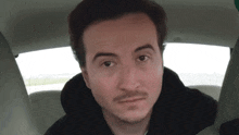 a man with a beard is sitting in a car looking at the camera