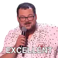 a man with glasses is holding a microphone and the word excellent is behind him