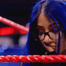 a woman with blue hair and glasses is in a ring