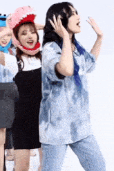 a woman wearing a sesame street hat is standing next to another woman wearing a tie dye shirt