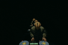 a large group of people are dancing in a dark room with a man standing in the middle with his arms in the air