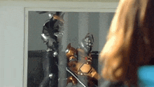a woman is looking at a picture of a robot in front of a mirror .