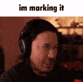 a man wearing headphones is making a funny face and the words im marking it are above him
