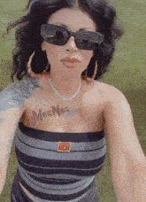 a woman wearing sunglasses has a tattoo on her chest that says mrs. nos