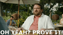 a man sitting at a table with the words oh yeah prove it written on the bottom