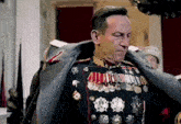 a man in a military uniform with a lot of medals on his chest is standing in a room .
