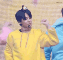 a man in a yellow sweatshirt with a stuffed animal on his head is dancing .