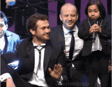 a man in a suit and tie is sitting next to another man and a little girl