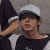 a young man wearing a baseball cap and a black shirt is being touched by another person .