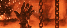 a close up of a person 's hand reaching out from a chain in a fire .
