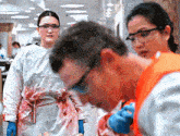 a woman in a bloody gown is standing next to a man wearing safety goggles