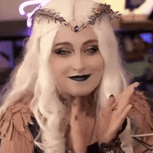 a woman in a costume with a crown on her head is making a funny face .
