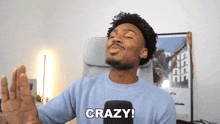 a man in a blue sweater says crazy in front of a black microphone