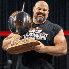 a man holding a trophy that says the longest man on earth
