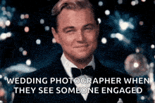 a man in a tuxedo and bow tie is smiling while a wedding photographer when they see someone engaged .