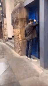 a man is knocking on a blue door with a sign that says ' a ' on it