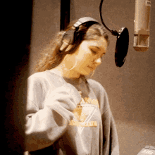 a woman wearing headphones stands in front of a microphone while wearing a shirt that says arizona