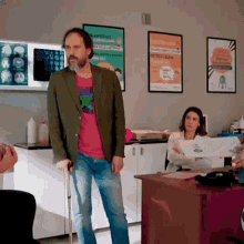 a man with crutches is standing in a room with posters on the wall including one that says ' a ' on it