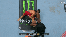 two men are fighting in front of a can of monster energy