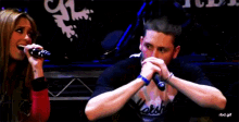 a woman singing into a microphone next to a man with a shirt that says worst on it