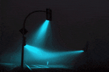 a street light is lit up at night with a blue light coming out of it