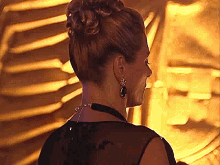 a woman with a bun on her head is wearing earrings and a black top