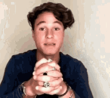 a young man with a ring on his finger is making a face .