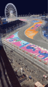 an aerial view of a race track with a ferris wheel behind it