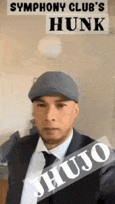 a man in a suit and hat is standing in front of a sign that says jhujo .