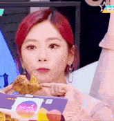 a girl with red hair is holding a box of food in her hand