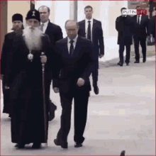 a man in a suit and tie is walking down a street with a cane .