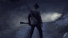 a man in a cowboy hat stands on train tracks holding a rifle