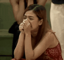 a woman in a red dress is crying and covering her face with her hands