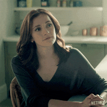 a woman is sitting at a table with a netflix logo on her wrist