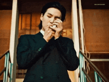 a man in a suit is smoking a cigarette while standing on stairs