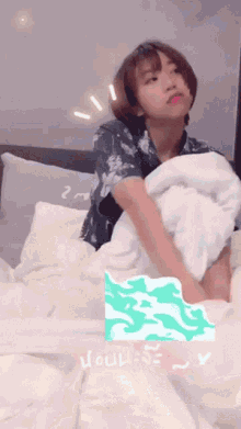 a woman is laying on a bed with a towel on her head and a sticker that says " you "