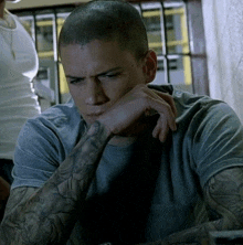 a man with a tattoo on his arm has his hand resting on his face