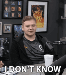 a man sitting in front of a microphone with the words " i don 't know " written on his face