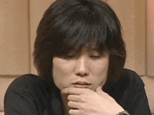 a close up of a person 's face with a hand on their chin