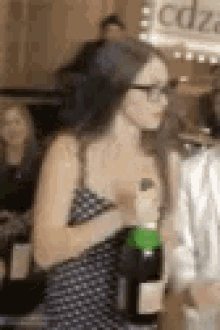 a woman in a polka dot dress is holding a bottle of champagne in her hand .