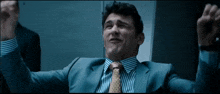a man in a suit and tie with his arms up