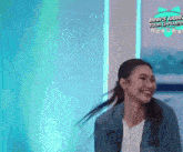 a woman in a ponytail is smiling in front of a blue background .