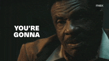a man in a suit says " you 're gonna " in white letters