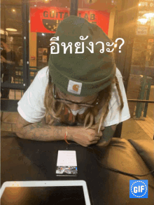 a man wearing a green beanie is looking at a cell phone