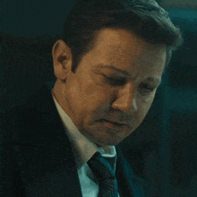 a man wearing a suit and tie is looking down