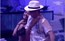 a man wearing a hat is holding a woman 's arm .