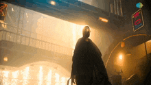 a man in a black cape stands in a dark room with a sign that says ' t.v. ' on it