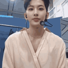 a young man wearing a robe and a microphone is standing in a room .