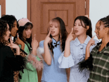 a group of girls are standing in front of a wooden door making funny faces