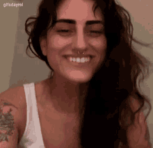 a woman with a tattoo on her arm is smiling with her eyes closed .